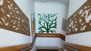 A staircase with ornate wooden railings and a green tree decal on the wall. - Richmart Resthouse (Barisal)