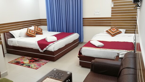 A hotel room with two beds, a small sofa, a telephone, and a colorful rug. - Richmart Resthouse (Barisal)