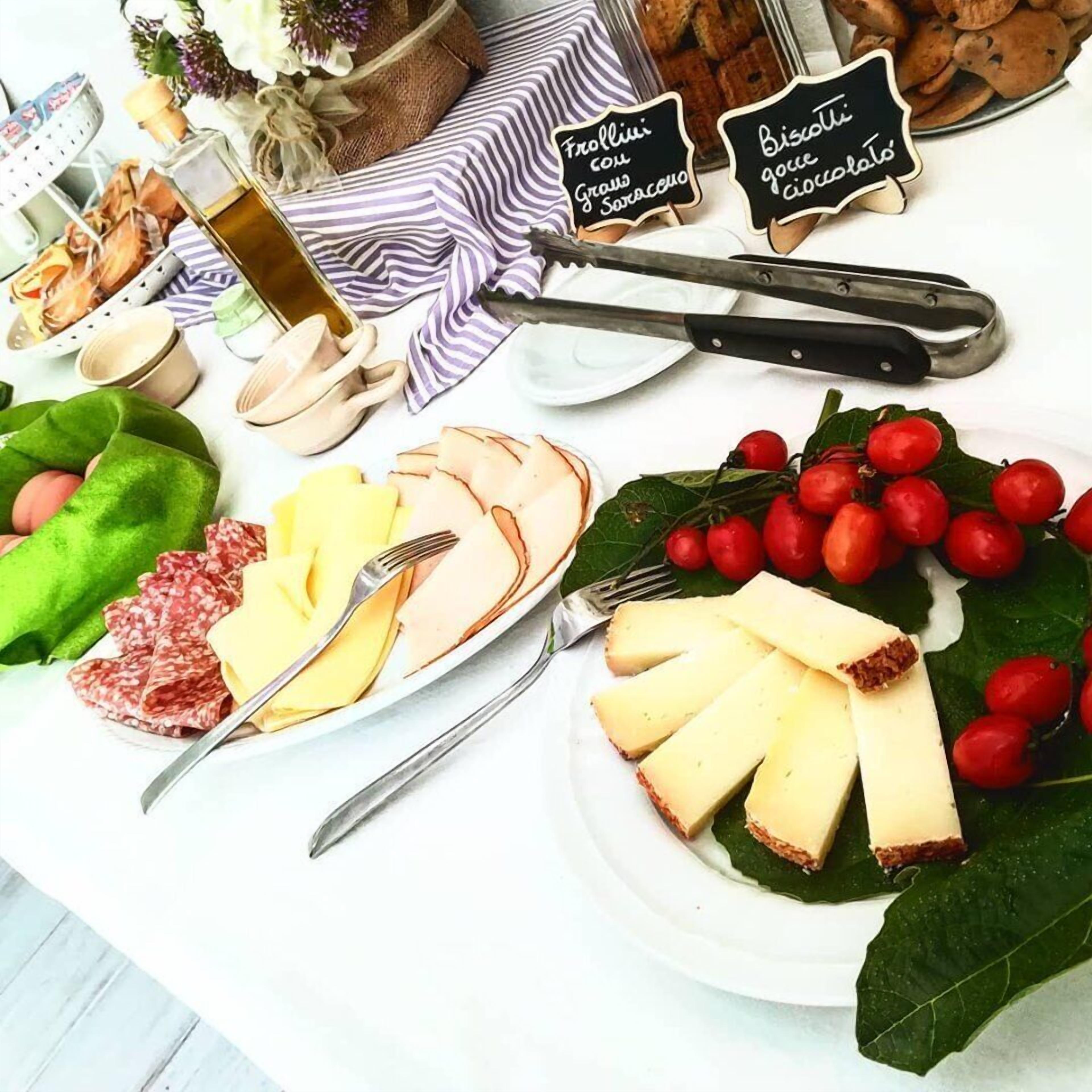 A table with various food items including cheese, cured meats, and berries, along with a bottle of olive oil and some bread.