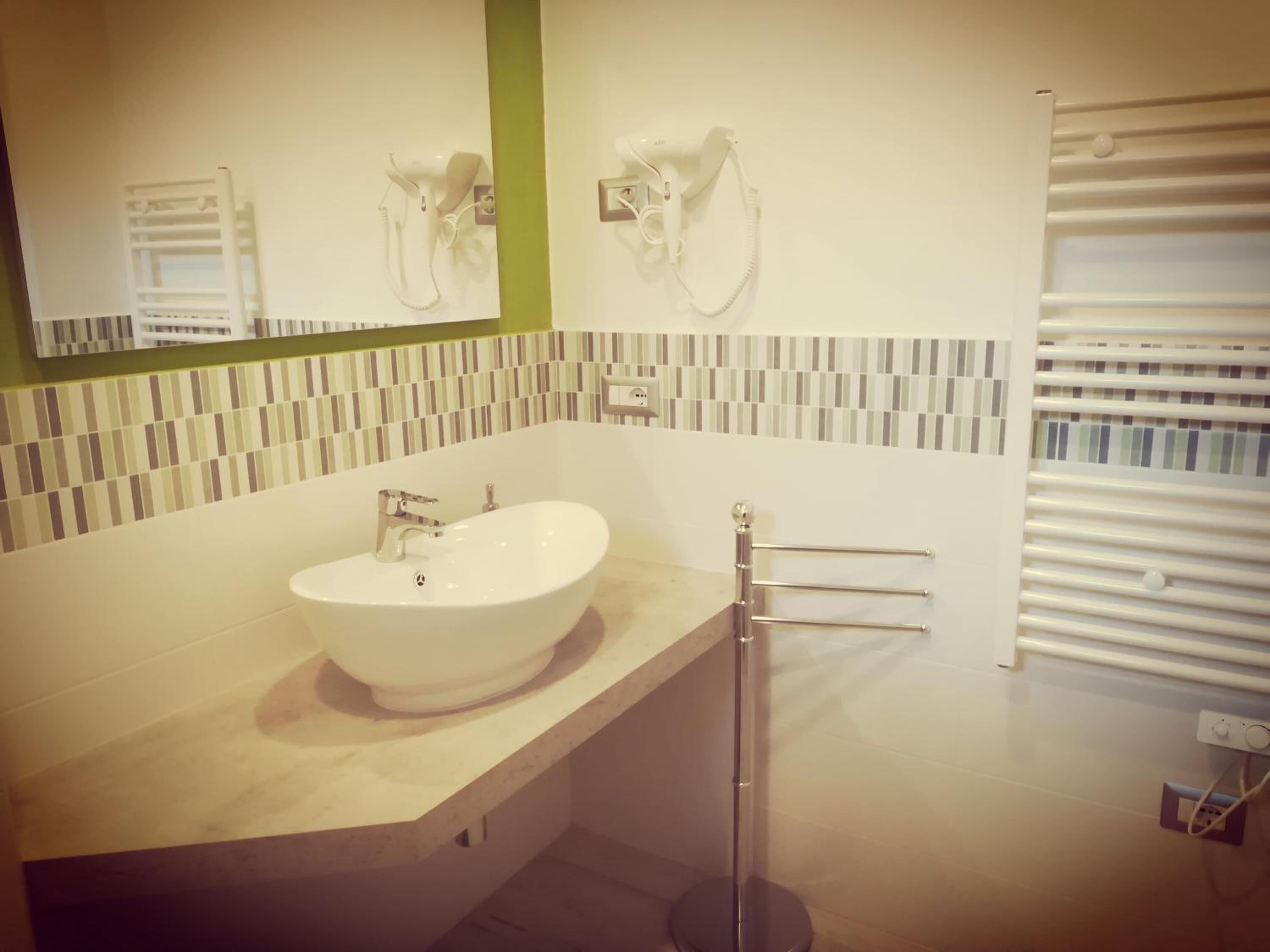 A modern bathroom with a large sink, a mirror, and a towel rack.
