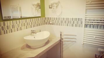 A modern bathroom with a large sink, a mirror, and a towel rack.