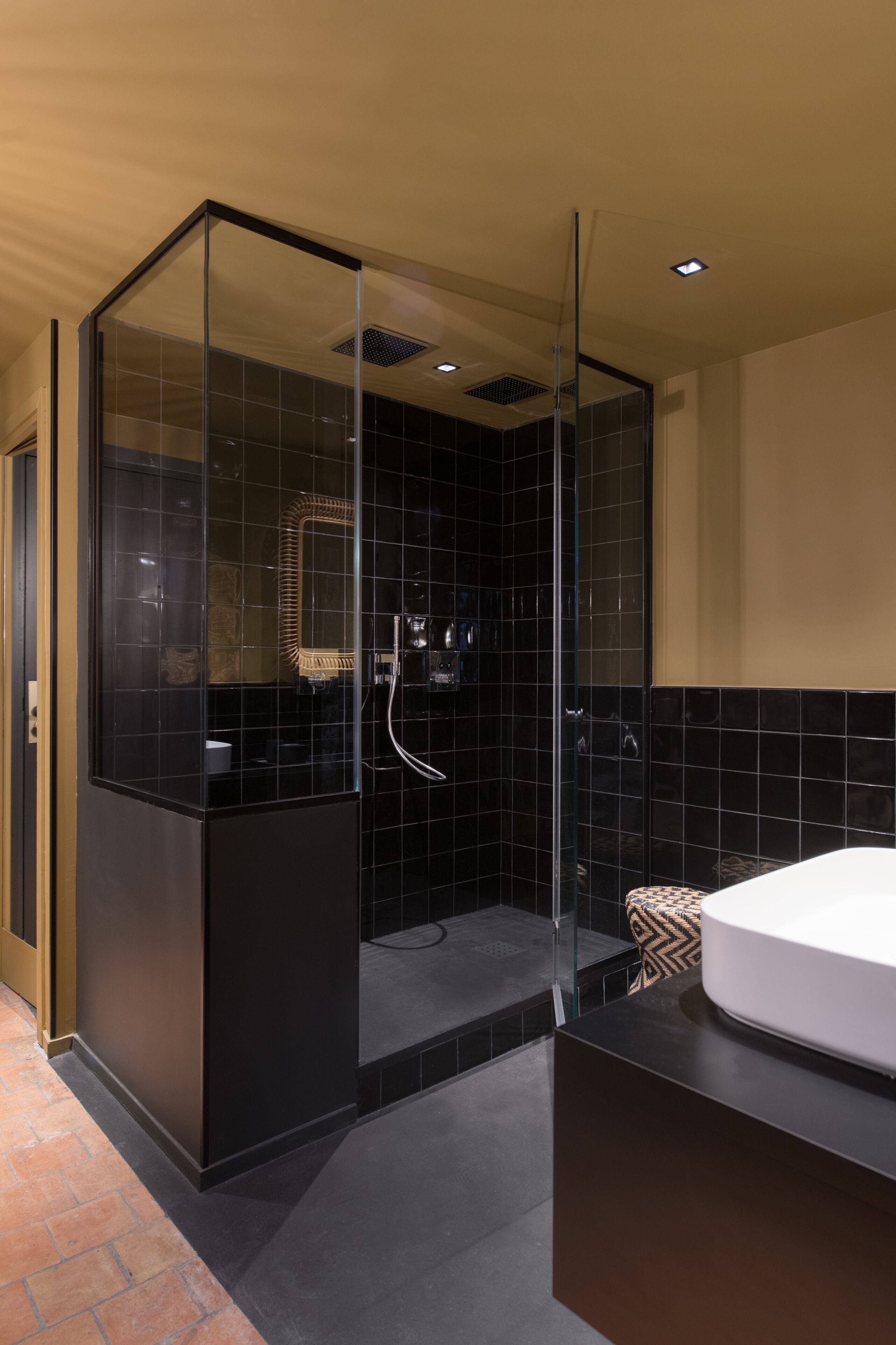 A modern bathroom with a glass-enclosed shower, a large mirror, and a white sink.