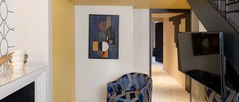 Una sala de estar moderna con alfombra azul, un sofá, una silla y un televisor.