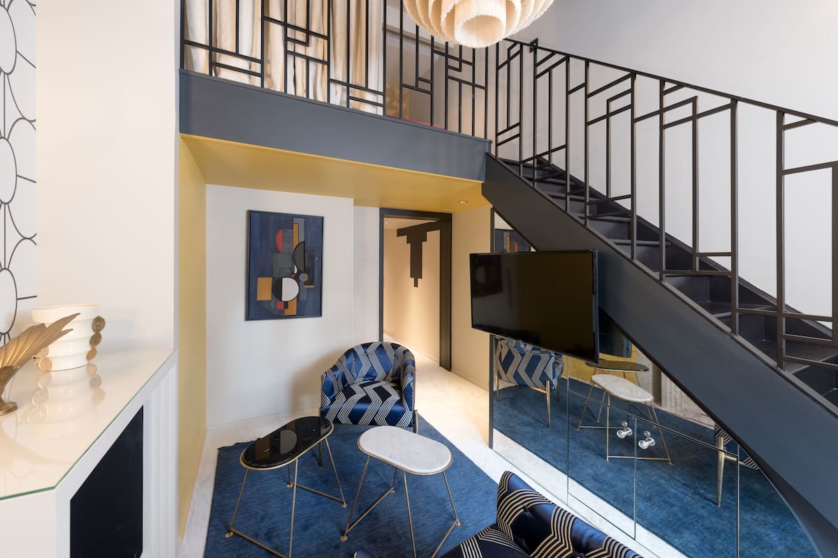 A modern interior with a staircase, seating area, and artwork.