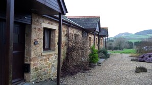 A stone building with a gravel driveway, a wooden door, and a window with a sign.
