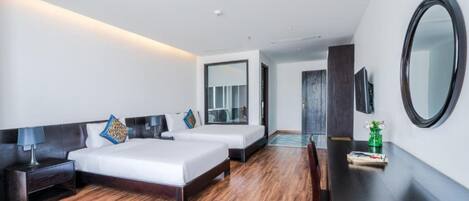 A modern hotel room with two beds, a desk, a mirror, and a TV.