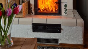A fireplace with a tiled surround and a basket of tulips on the mantel.