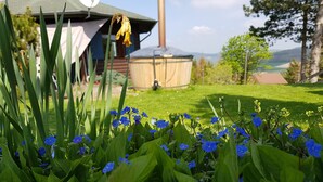 A garden with blue flowers and green foliage in front of a building with a chimney.