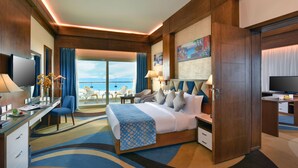 Hotelkamer met een groot bed, een bureau, een televisie en uitzicht op zee.