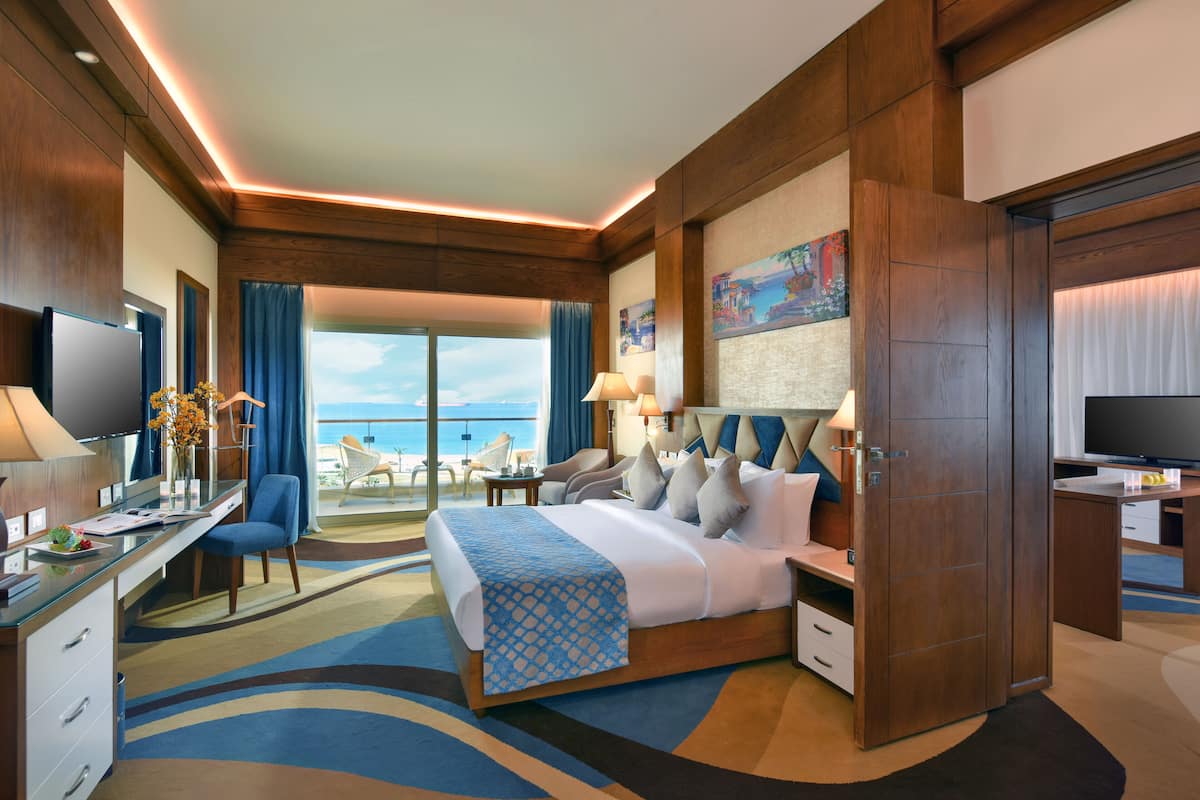 Hotelkamer met een groot bed, een bureau, een televisie en uitzicht op zee.