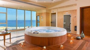 Een moderne spa ruimte met een ruime hottub, houten lambrisering en uitzicht op de oceaan.