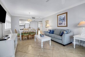 A living room with a sofa, coffee table, and dining area with chairs.