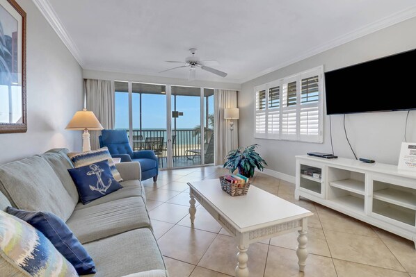 A living room with a sofa, a coffee table, a TV, and a balcony with a view.