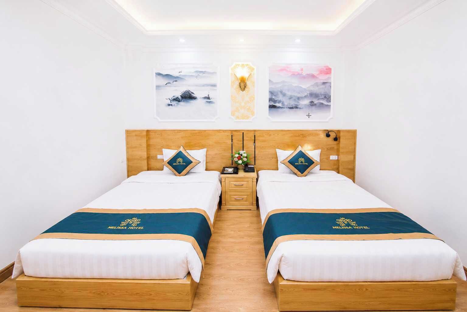 Une chambre d’hôtel avec deux lits, des têtes de lit en bois, du linge de lit blanc et des œuvres d’art accrochées aux murs.