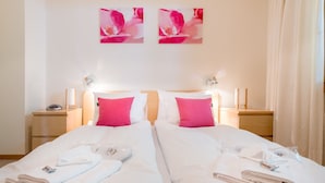 Ein Hotelzimmer mit einem Doppelbett, zwei rosa Kissen, Nachttischen mit Lampen und einem Bild an der Wand.