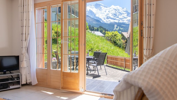 Ein Zimmer mit einer großen Schiebetür, die auf eine Terrasse mit Blick auf die Berge führt.