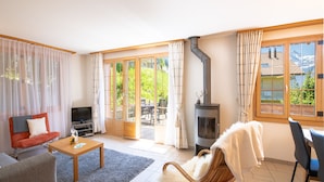 Ein Wohnzimmer mit einer Couch, einem Fernseher, einem Kamin und einem Essbereich mit Stühlen.
