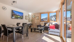 A modern living room with a dining area, large windows, and a view of a mountainous landscape. - Chalet Belmont - perfect location, recently new (Wengen)