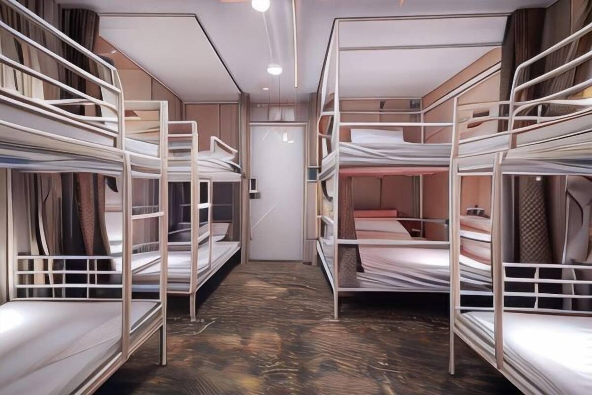 A room with bunk beds arranged in a U-shape, a door in the center, and a patterned carpet.