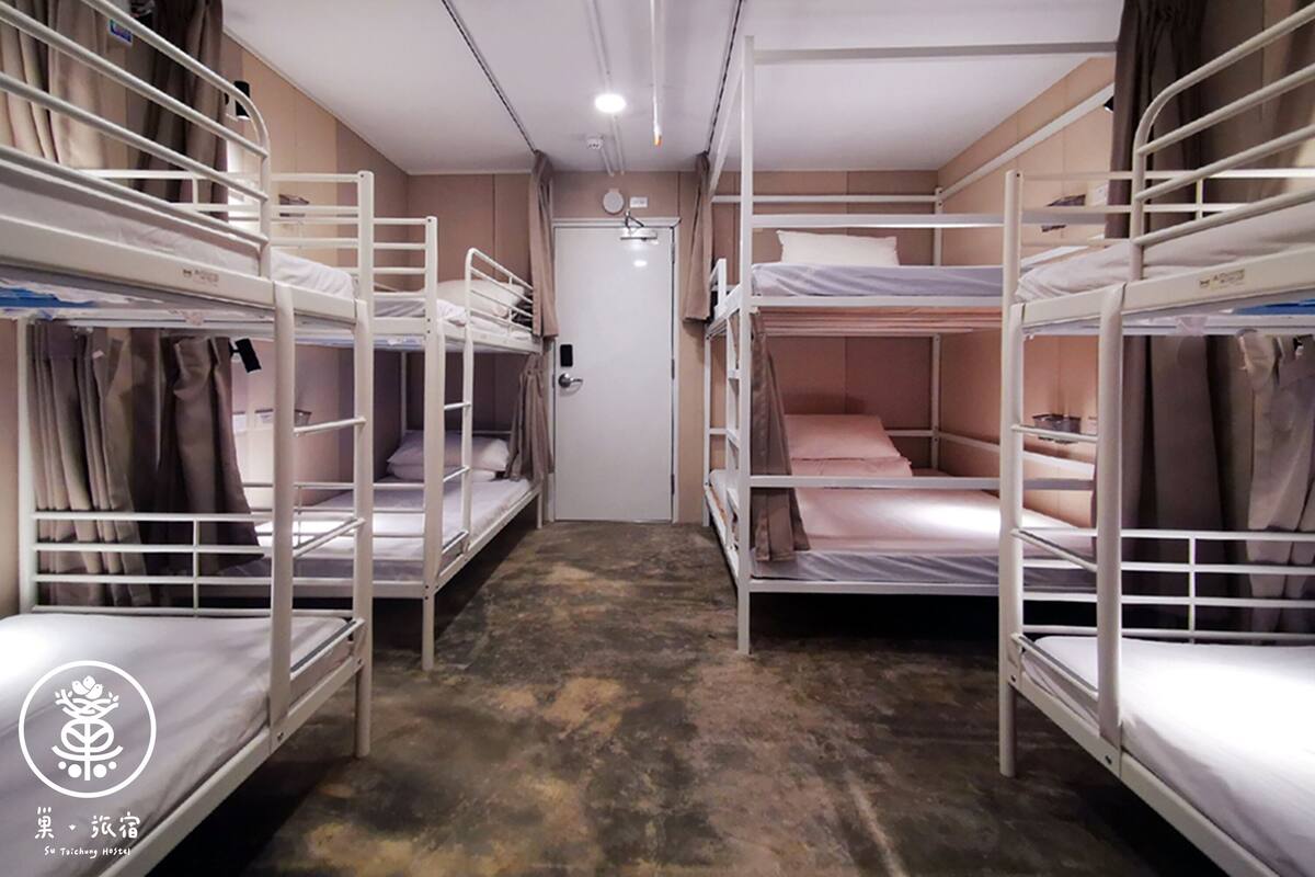 A dormitory room with bunk beds, a door, and a ceiling light.