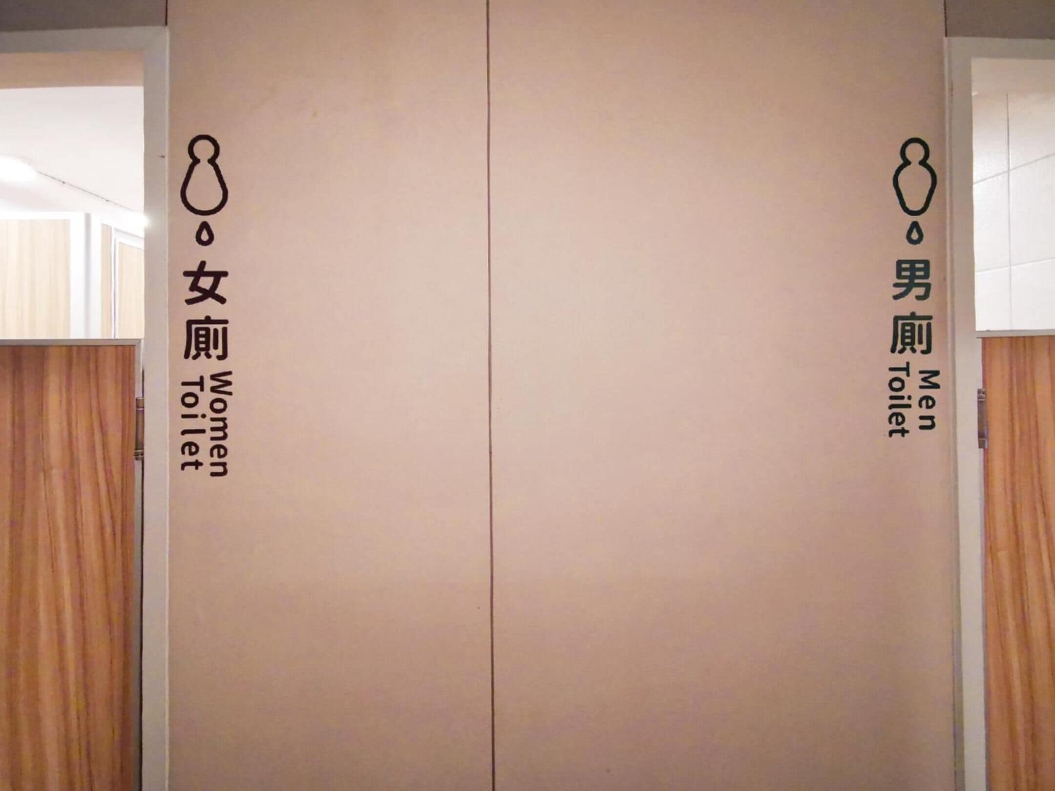 A restroom with a sign indicating a women's toilet on the left and a men's toilet on the right.