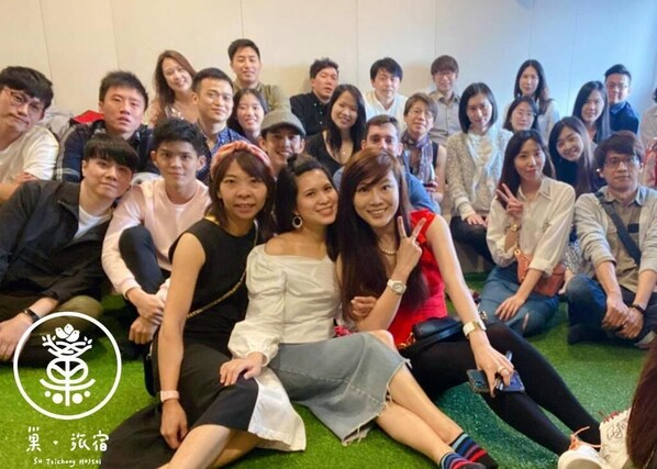 A group of people sitting on a green carpeted floor in a room with white walls.