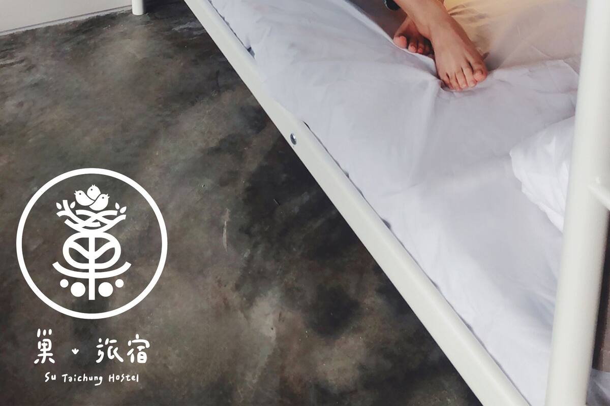 A bunk bed with a person sitting on the lower bunk, holding a smartphone.