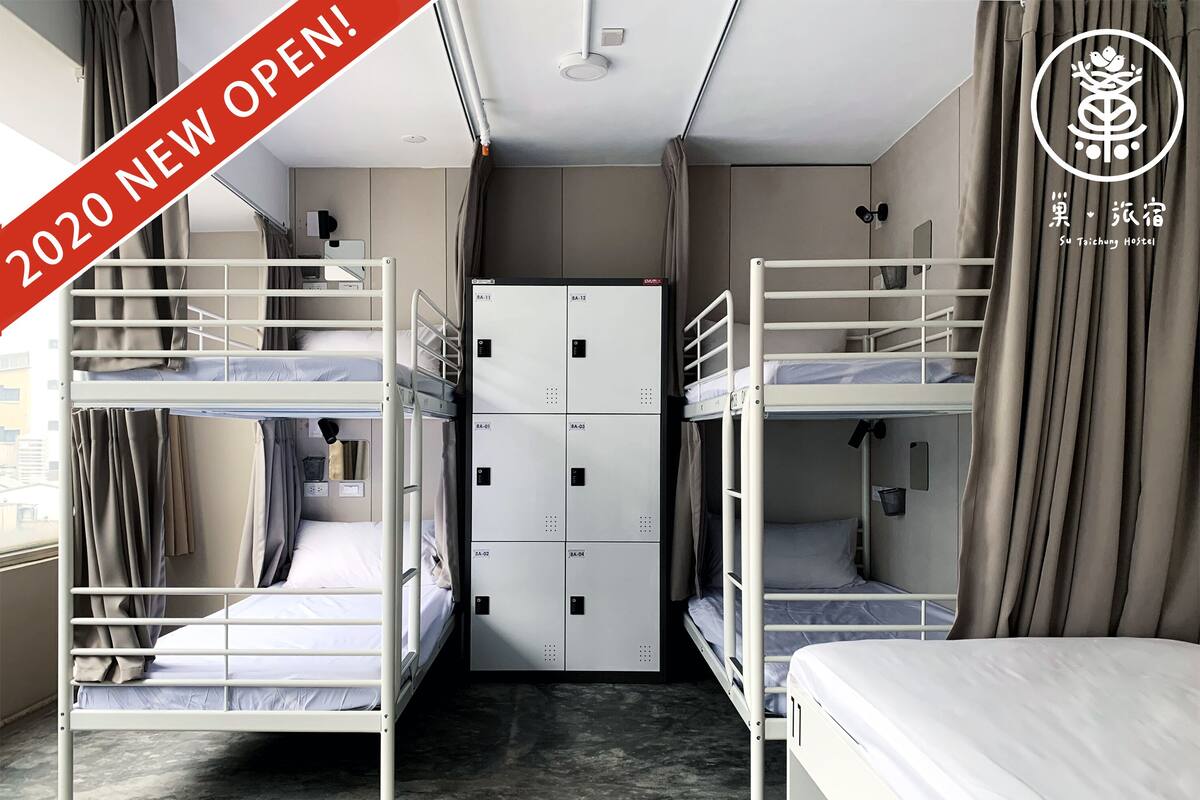 A dormitory room with bunk beds, a wardrobe, and a curtain.
