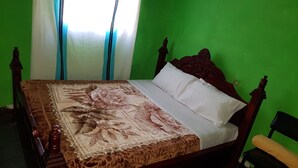 A bed with a floral bedspread and white pillows in a room with green walls and a wooden headboard. - Abrham Lalibela Home Stay (Lalibela)