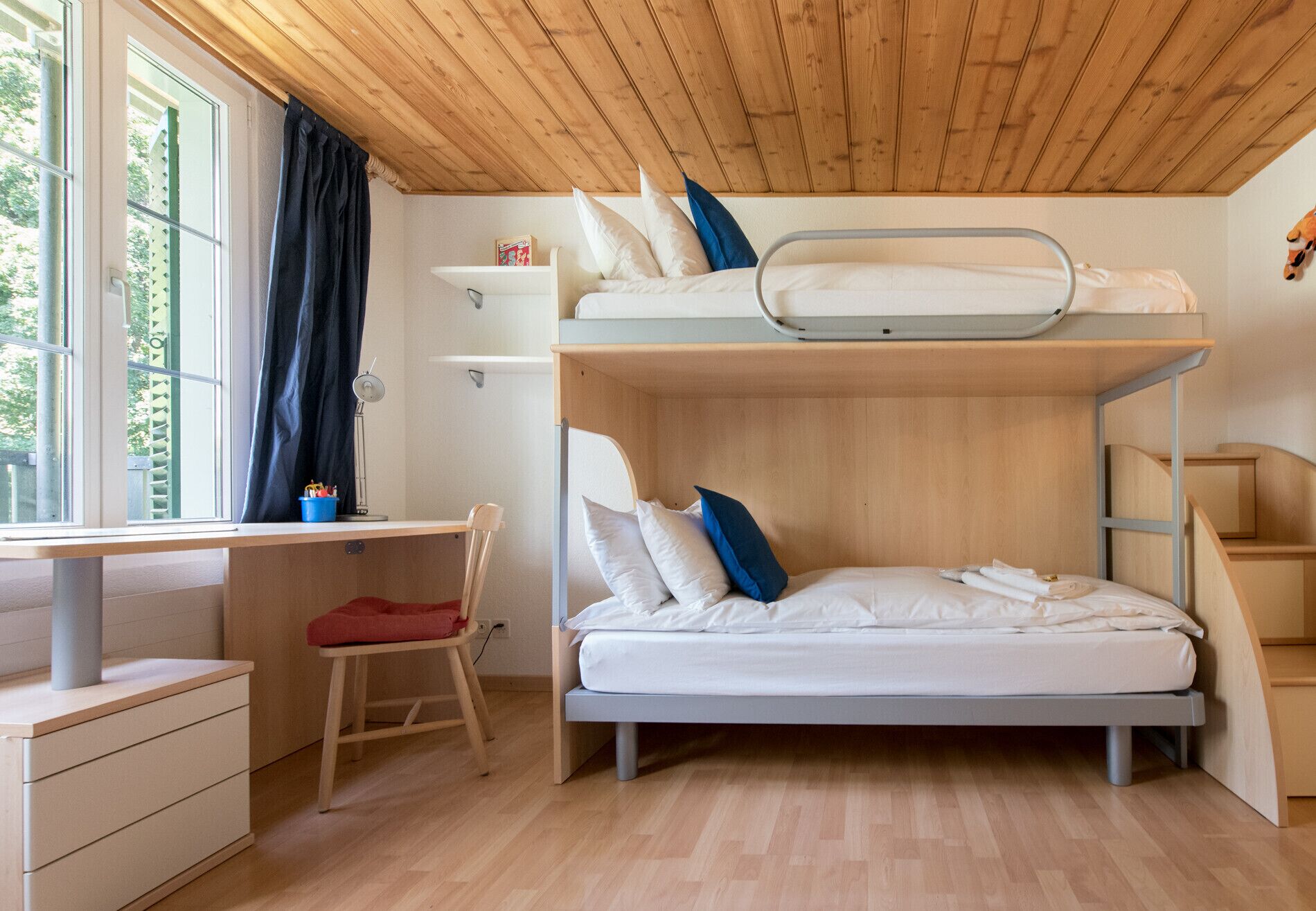 Une petite pièce comprenant un lit superposé, un bureau et une chaise.