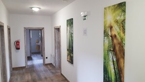 A hallway with wooden flooring, a fire extinguisher, and two doors. - Pension Pek (Kubova Hut)
