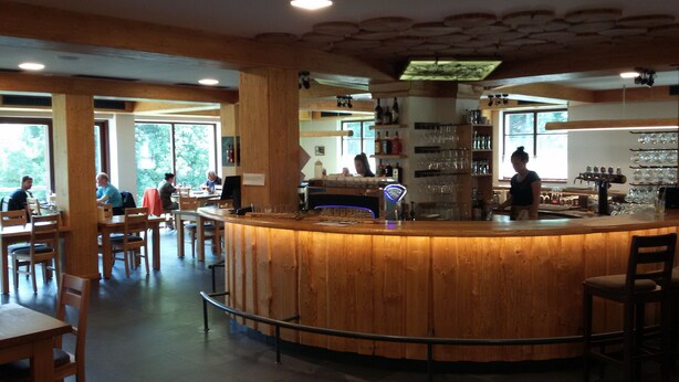 A wooden bar area with a counter, seating, and a view of the outdoors. - Pension Pek (Kubova Hut)