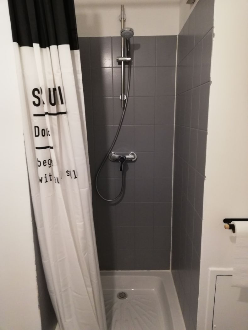 A shower with a handheld showerhead and a wall-mounted faucet.