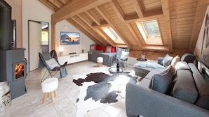 Ein gemütliches Lofts-Wohnzimmer mit Kamin, Sitzgelegenheit und Dachfenstern.