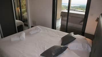 Une chambre d’hôtel avec un lit, des oreillers, une fenêtre et un balcon.