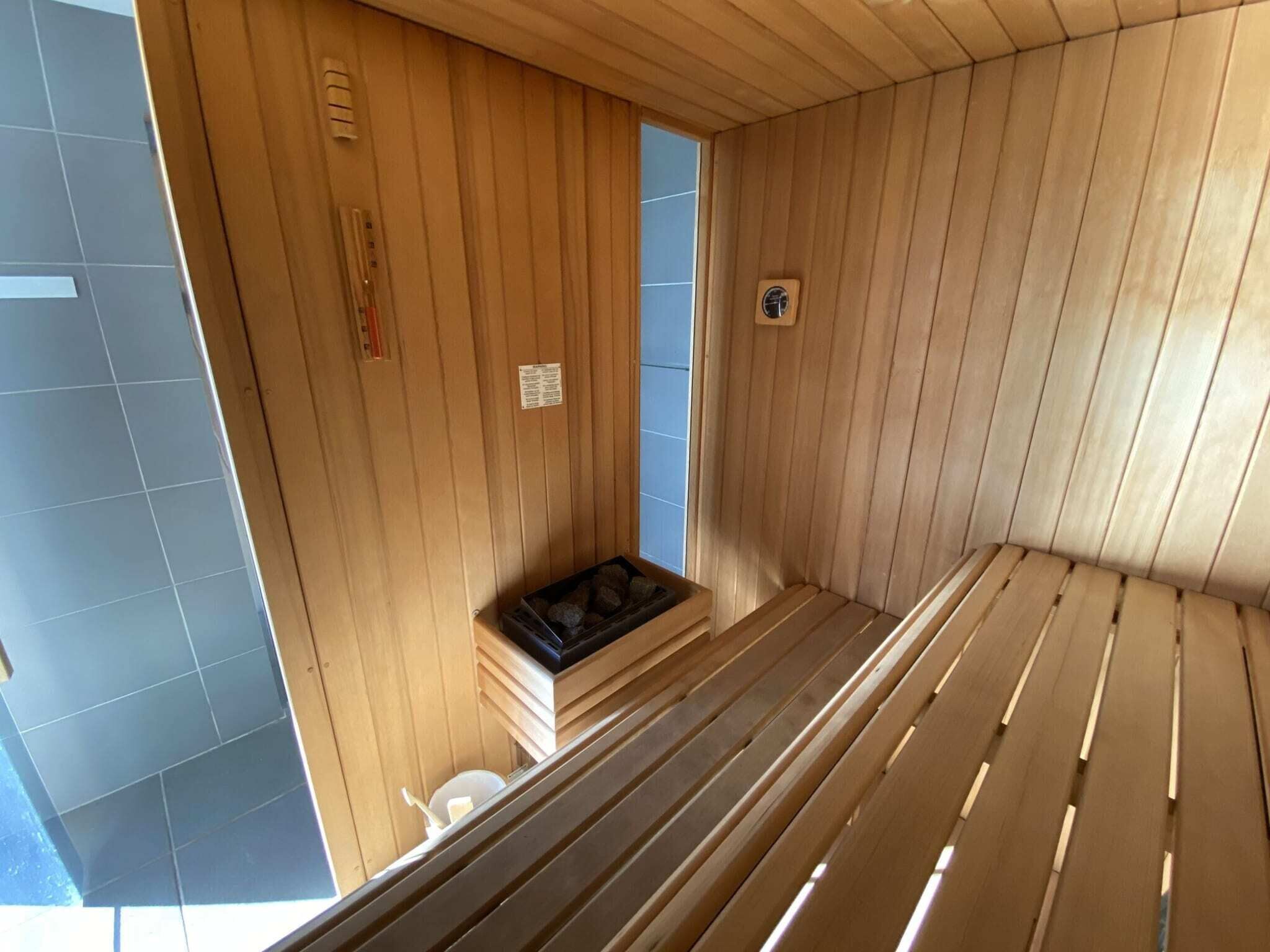 Eine Holzsauna mit einer Bank, einer kleinen Sitzbank und einem Wandofen.
