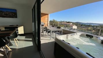 Un balcón con jacuzzi, zona de comedor y vistas al paisaje.
