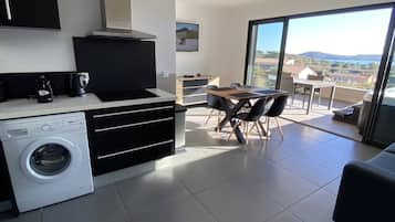 Una cocina moderna con lavadora integrada, un comedor con vistas y un balcón con paisaje panorámico.