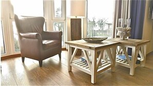Une pièce comprenant un fauteuil en cuir, une table en bois avec un bol, et une lampe.