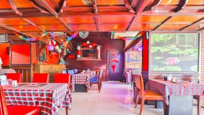 Ein Restaurant mit rot-weißen karierten Tischdecken, Holztischen und festlicher Dekoration.