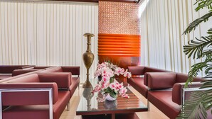 Eine moderne Lobby mit roten Ledersofas, einem Glastisch und einer dekorativen Vase mit Blumen.