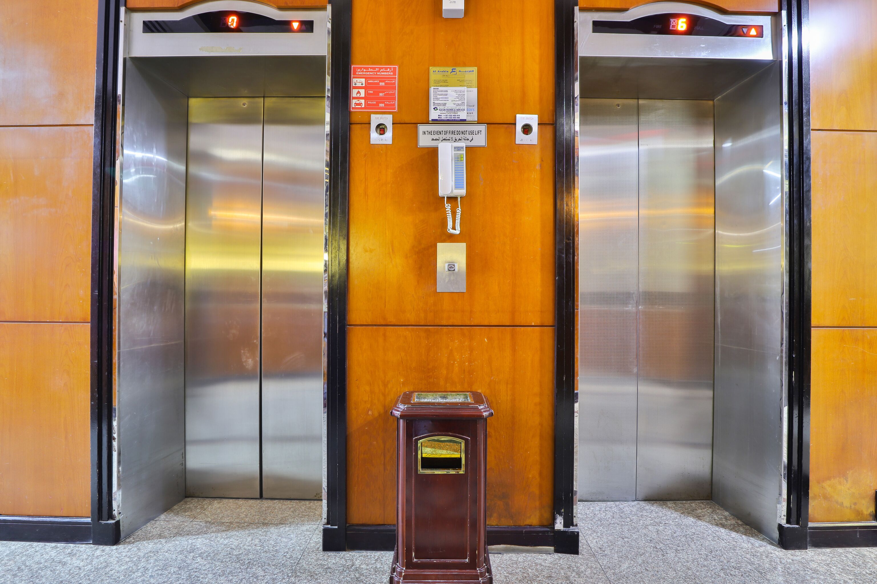 An elevator with a wooden panel and a call button.