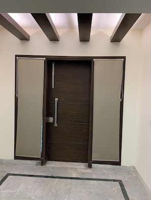 Enter through the door with a metallic handle, flanked by two panels, into a space with a skylight above.