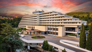 A multi-story hotel with a central courtyard, a swimming pool, and a view of a river. - Interhotel Sandanski (Sandanski)