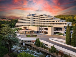 Um hotel com vários andares, um pátio central, piscina e vista para um rio.