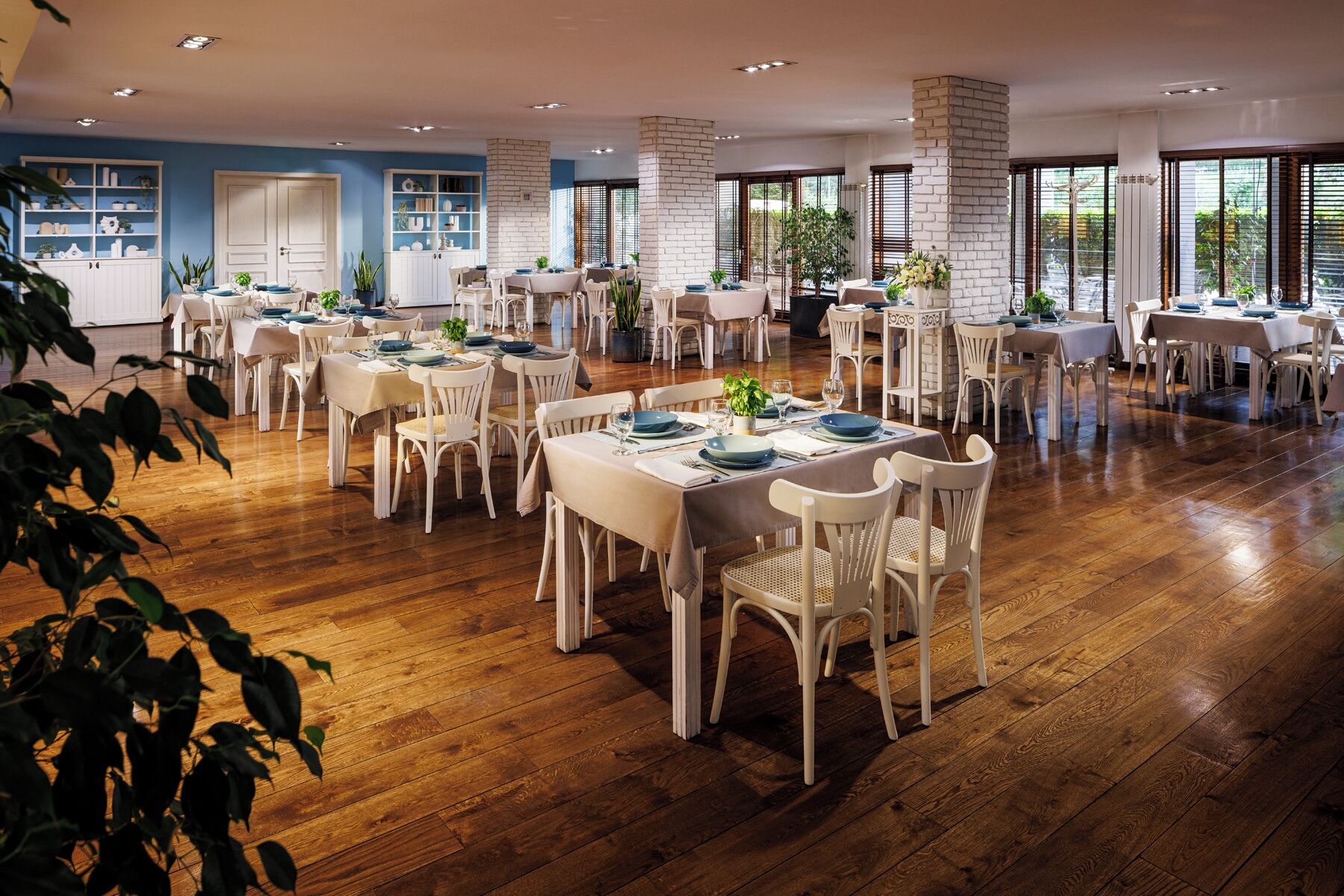 A spacious dining area with multiple tables and chairs, white brick pillars, and large windows allowing natural light.