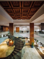 Interior espaçoso com uma imponente escadaria, teto em painéis de madeira e mobiliário moderno.
