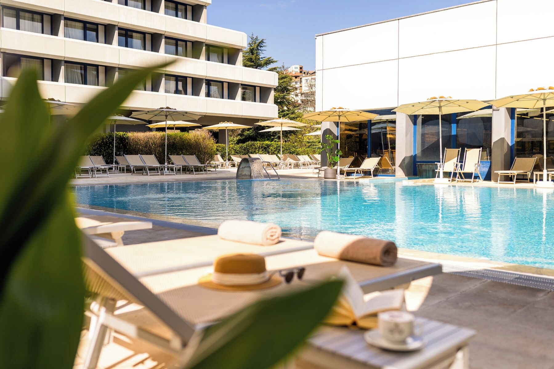 Una piscina techada, una piscina al aire libre, sombrillas