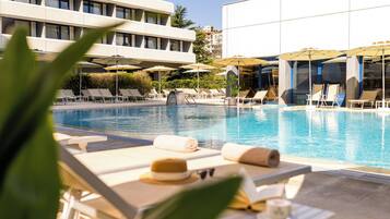 Una piscina techada, una piscina al aire libre, sombrillas