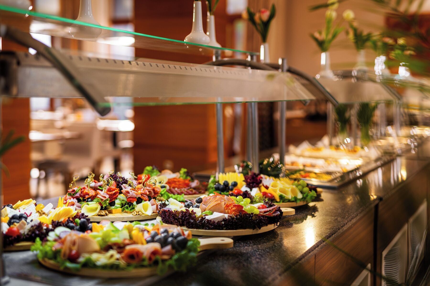 A buffet with various food items including meats, cheeses, and fruits.